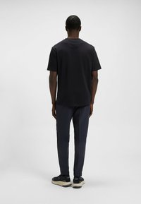 Black short-sleeved t-shirt with a straight cut, paired with navy slim-fit pants featuring a smooth texture and tapered cuffs.