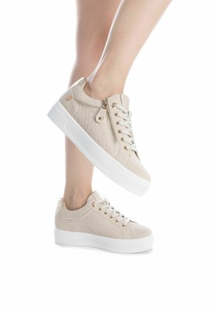 Zapatillas beige con textura acolchada, herrajes en tono dorado y una suela blanca gruesa; cuentan con cordones y un zipper lateral para facilitar su uso.