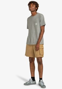 Gray short-sleeve t-shirt with a chest pocket, paired with tan cargo shorts featuring side pockets. Gray sneakers with white accents.