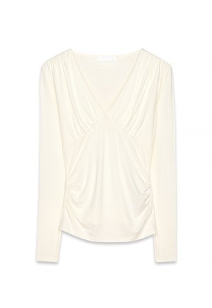 Lange mouwen crèmekleurige blouse met V-hals, geplooide stofdetails bij de buste en zijkanten, en een zachte, licht gedrapeerde silhouet.