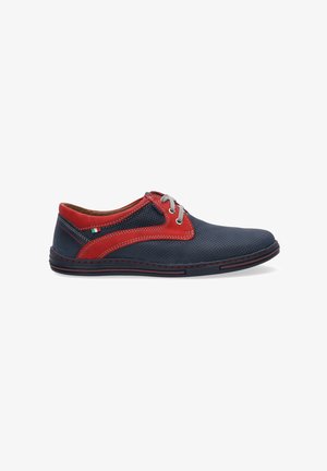 Navy blue perforated leather shoe with red suede accents, gray laces, and white stitching. Low profile design with a textured surface.