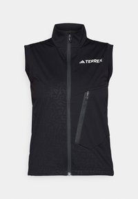 Black sleeveless vest featuring a high collar, front zipper, and a diagonal zip pocket. Subtle geometric patterns across the fabric.