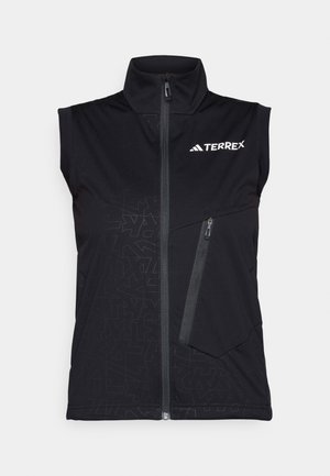 Svart ermeløs vest med høy krage, frontglidelås og diagonalt glidelåslomme. Diskrete geometriske mønstre over stoffet.
