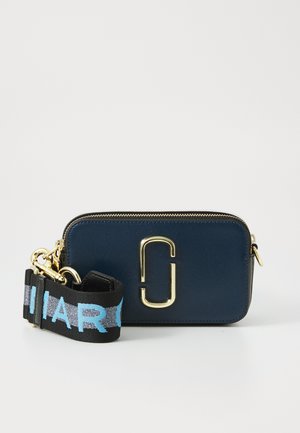 Sac en cuir synthétique bleu marine avec quincaillerie dorée, fermeture éclair et bandoulière noire avec texte bleu. Forme rectangulaire compacte.