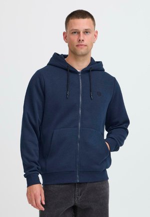 Navy zip-up hoodie made of soft fabric, featuring a front pocket, adjustable drawstring hood, and black logo detail on the chest.