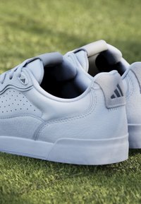 Light blue sneakers made of smooth leather with perforated design, rounded toe, and rubber soles; features padded collar and logo on heel.