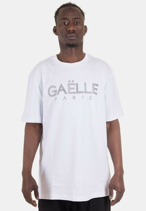 T-shirt bianco a maniche corte con la scritta "GAËLLE PARIS" in lettere nere, bold e puntinate sul petto. Tessuto morbido, vestibilità rilassata.