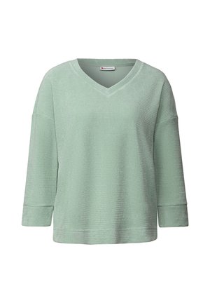 Pull vert menthe avec un col en V, manches trois-quarts, tissu texturé et coupe décontractée. Étiquette visible au niveau du col.