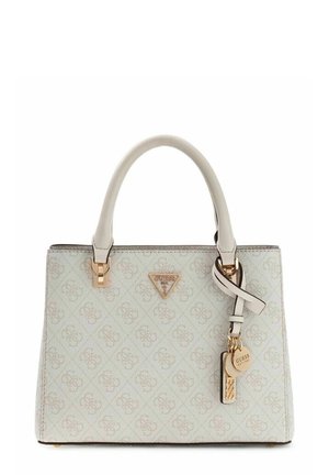 Crèmekleurige Guess-handtas met monogrammotief, dubbele handgrepen en goudkleurige logohangers die aan de rechterhandgreep hangen.