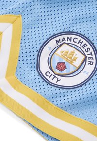 Lichtblauwe gaasstof met gele en witte gestreepte accenten. Bevat een cirkelvormig logo van Manchester City met een schip en rozenontwerp.