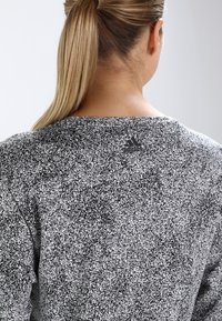 Czarnobiały melanżowy top z długim rękawem i szerokim dekoltem, z logo Adidas umieszczonym z tyłu przy szyi.