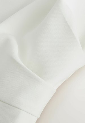 Weißer Stoff mit glatter Textur und subtilen Falten, die Nahaufnahmen der Materialstruktur und Weichheit zeigen.