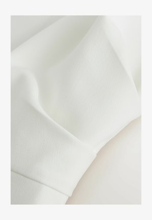 Weißer Stoff mit glatter Textur und subtilen Falten, die Nahaufnahmen der Materialstruktur und Weichheit zeigen.