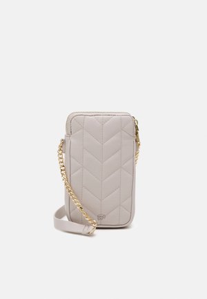 Mała beżowa pikowana torebka na ramię z złotym łańcuszkiem i zamkiem błyskawicznym, zaprojektowana do noszenia niezbędnych rzeczy.