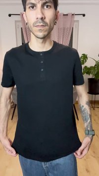 Black short-sleeve polo shirt with a henley neckline and three buttons, made of lightweight fabric; worn with light blue jeans.