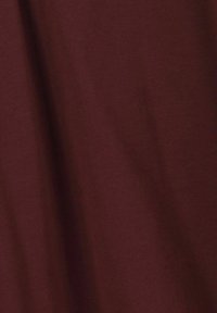 Tissu bordeaux avec une texture lisse et douce ; couleur unie sans motifs apparents. Le matériau semble léger et légèrement drapé.