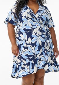 Námořnická modrá zavinovací šaty s květinovým printem v světle modré a bílé. Mají krátké rukávy, volánkový lem a zavázaný pás pro nastavitelný střih.