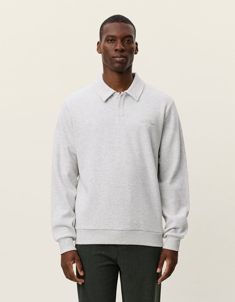 Szürke pulóver, gallérral, hosszú ujjú és bordás mandzsettával. Diszkrét logó részlet a mellkason és puha textúra.