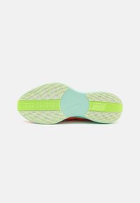 Semelle de chaussure Nike en caoutchouc vert menthe avec une adhérence texturée, un design segmenté et des accents rouges vifs sur la semelle intermédiaire.