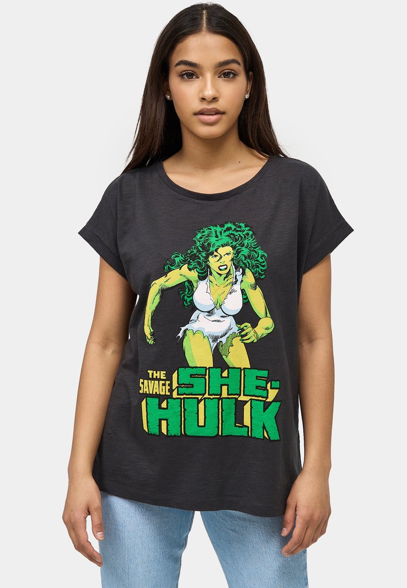 Camiseta de manga corta gris oscuro hecha de algodón, con un gráfico verde y amarillo de She-Hulk y un texto en negrita debajo.