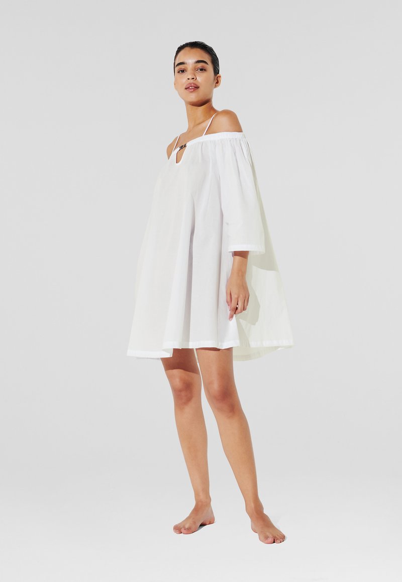 Witte off-shoulder jurk met een sleutelgatdetail en driekwartmouwen. Gemaakt van lichtgewicht stof, met een losse, vloeiende snit.