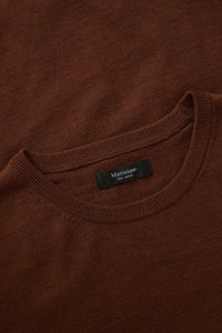 Barna merinó gyapjú pulóver kerek nyakkivágással. Száraz tapintású felület és bordázott mandzsetták jellemzik. A címkéjén ez olvasható: „Matinique 100% Merino.”