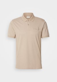 Beige polo-shirt lavet af bomuld med krave med to knapper, korte ærmer og et broderet logo på brystet. Glat tekstur.