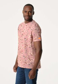 Korte mouwen roze t-shirt met een bladdessin in roomkleurig, blauw en oranje. Gemaakt van zacht materiaal, met een klein oranje logo op de mouw.