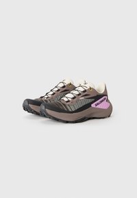 Brune og svarte joggesko med mesh-overdel, hvite detaljer, lilla logo, og teksturert gummisåle. Har gule snøringøyer og lisser.