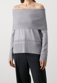Maglione grigio scollato sulle spalle con collo a coste e maniche lunghe. Texture liscia con dettagli a motivo orizzontale sul corpo.