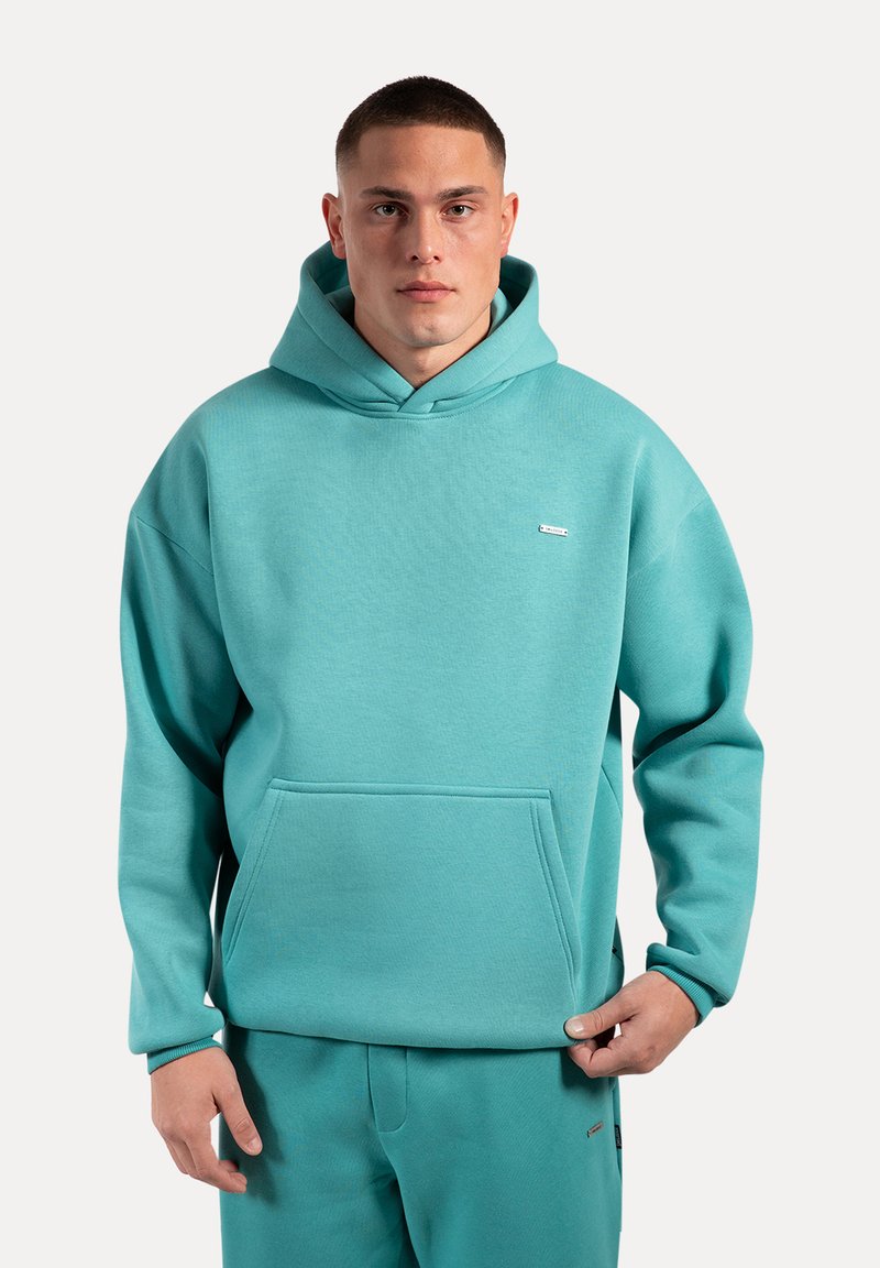 Turkis hoodie lavet af blødt stof, med snor i huen, frontlomme i kenguru-stil og minimal logo-detalje på brystet.