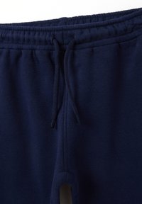 Pantalones de chándal de algodón azul marino con cintura elástica, cordón ajustable y bolsillos laterales. Textura suave con un diseño sencillo.