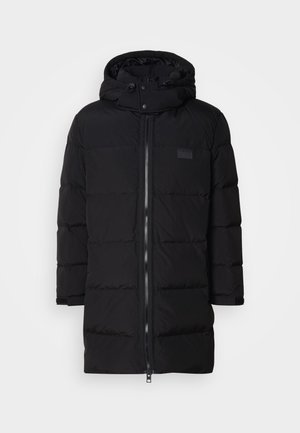 Casaco puffer preto com fecho frontal, capuz e punhos elásticos. Apresenta seções acolchoadas e um pequeno logótipo no peito.