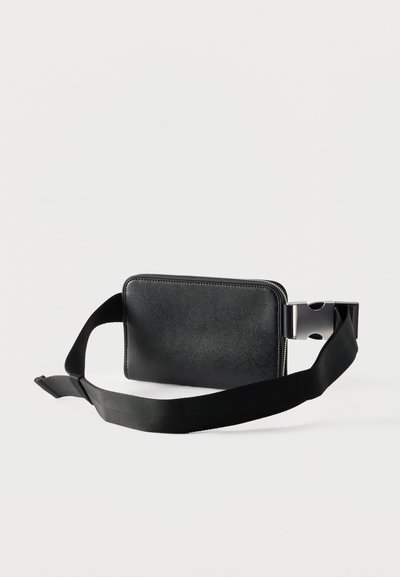 Sac banane en cuir noir texturé avec fermeture éclair et sangle noire réglable dotée d'une boucle en plastique argenté.