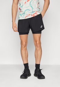 Black running shorts with built-in inner liner, lightweight fabric, and a logo on the left side. Paired with black athletic shoes and socks.