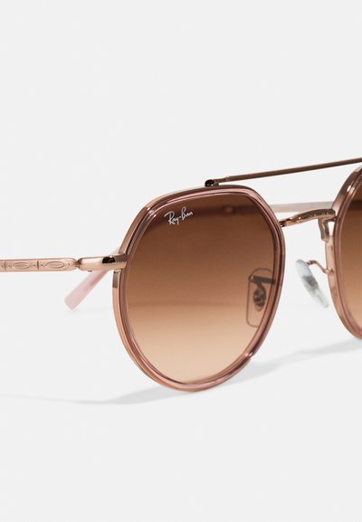 Слънчеви очила Ray-Ban с розова осмоъгълна рамка, градиентни кафяви лещи, метални акценти и прозрачни носови подложки; стилни детайли от метал.