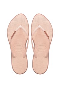 Tan rubber flip-flops with textured soles, thin straps, and a decorative rose gold accent on the left strap. Size indicated as 37-38.