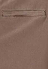 Bruine stof met horizontale strepen, met een rechthoekige paspelzak met een smalle omranding. Vlotte textuur met een subtiele glans.