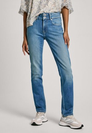 Helle blaue gerade geschnittene Jeans mit hoher Taille und zwei Knöpfen. Getragen mit einer blumigen Bluse und hellen Sneakers.