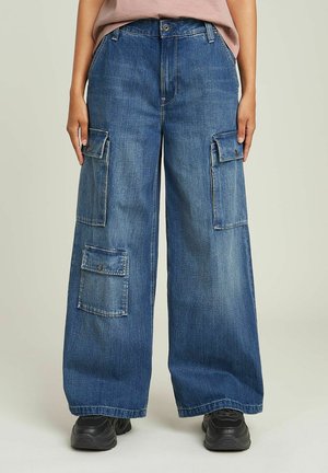 Pantaloni cargo in denim blu a gamba larga con molteplici tasche, chiusura a bottone e cuciture visibili. Il tessuto ha una lavatura media e una texture liscia.