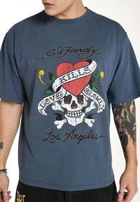 Blue cotton t-shirt featuring a skull graphic with a heart and banner design that reads "LOVE KILLS SLOWLY" and "Los Angeles" in bold letters.