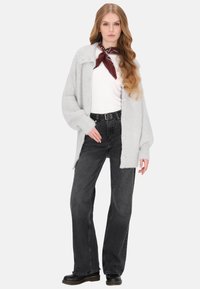 Cardigan tricotat gri deschis cu nasturi mari, purtat peste o cămașă albă și blugi negri cu talie înaltă. Prezentând o eșarfă roșie cu un model.