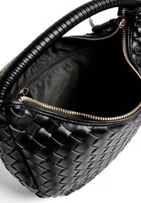 Svart vävd läderhandväska med en strukturerad form, en dragkedjeöppning och ett rymligt inre fodrat i svart tyg. Detaljer i guldton.