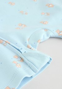 Vêtement pour bébé bleu clair avec une fermeture éclair et de petits motifs d'oursons portant des tenues rayées, présentés au niveau de l'emmanchure et du poignet.