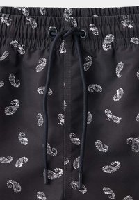 Shorts noirs à taille élastique avec un motif paisley blanc et un cordon noir noué au centre devant.