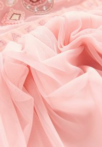 Rosa Tüllstoff mit weicher, fließender Textur und subtiler Lichtreflexion, ausgestattet mit dekorativen Elementen und bestickten Akzenten.