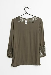 Olivgrön topp med trekvartslånga spetsärmar, nyckelhål bak och vågig nederkant. Mjuk tyg med blommig spetsdetalj.