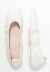 Vita läder platta skor med en fyrkantig tådesign, mjuk textur och en slät innerfoder. Klackarna är låga och rundade.