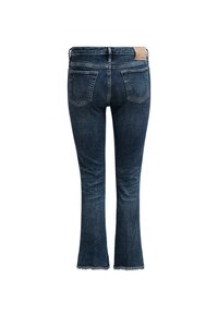 Jean flare en denim bleu avec un ourlet effiloché, deux poches arrière et un patch en cuir à la taille. Offre un look classique et texturé.