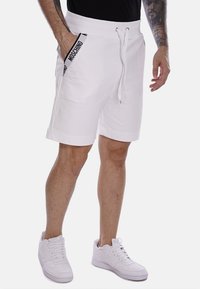 Pantaloni corti bianchi in cotone con vita regolabile tramite cordino, tasche laterali e accenti neri a contrasto. Tessuto morbido e vestibilità regolare.